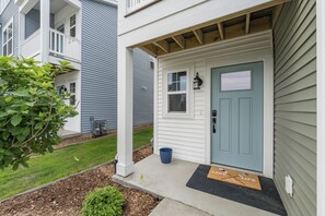 A two-story house with a blue front door, a small porch, and a welcome mat. - Beach Glass Bungalow- new build close to beach and park (South Haven)