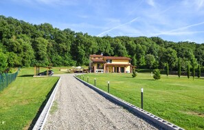 Ein zweistöckiges Gebäude mit Ziegeldach, umgeben von einer gepflegten Rasenfläche und einem Kiesweg, der dorthin führt.
