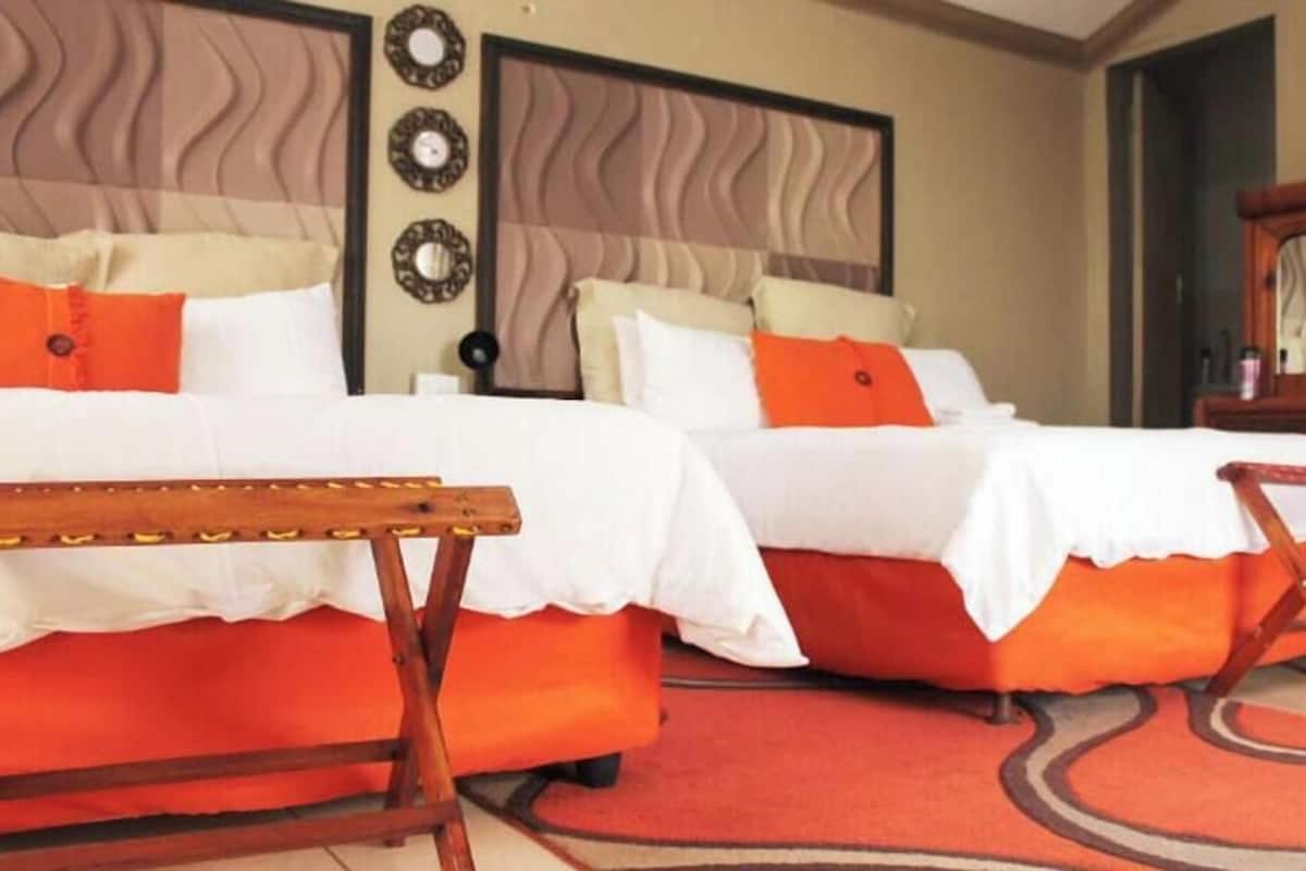 Habitación de hotel con dos camas, un banco de madera y una alfombra roja.