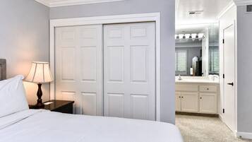 Un dormitorio con cama, una mesita de noche con lámpara y un armario con espejo.