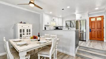A kitchen with white cabinetry, a dining table set for six, and a stainless steel refrigerator.