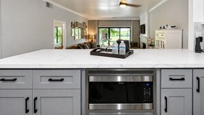 Una cocina moderna con una isla grande, microondas integrado y electrodomésticos de acero inoxidable.