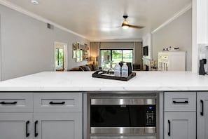 A modern kitchen with a large island, built-in microwave, and stainless steel appliances.