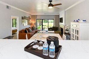 Una habitación de hotel con comedor, sofá, televisión y chimenea.