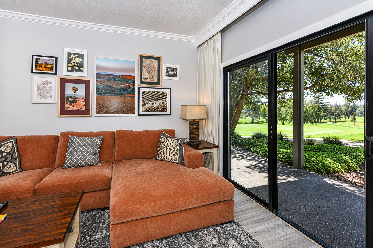 Una sala de estar moderna con un sofá seccional, una mesa de centro y un ventanal con vistas a un campo de golf.