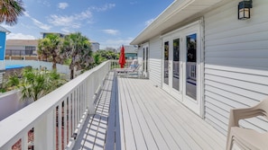 A wooden deck with white railings, a red umbrella, and outdoor furniture. - Turtlemound Terrace - Your Favorite Beach Getaway (New Smyrna Beach)
