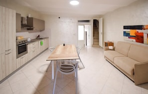 Une cuisine moderne avec une table et des chaises, un canapé et un escalier menant à un autre niveau.