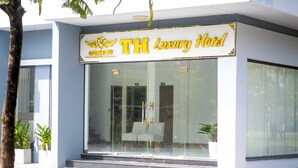 Un edificio moderno con un letrero que dice 'TH Luxury Hotel' y un número de contacto.