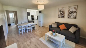 Ein modernes Wohnzimmer mit Sofa, Couchtisch und Essbereich.