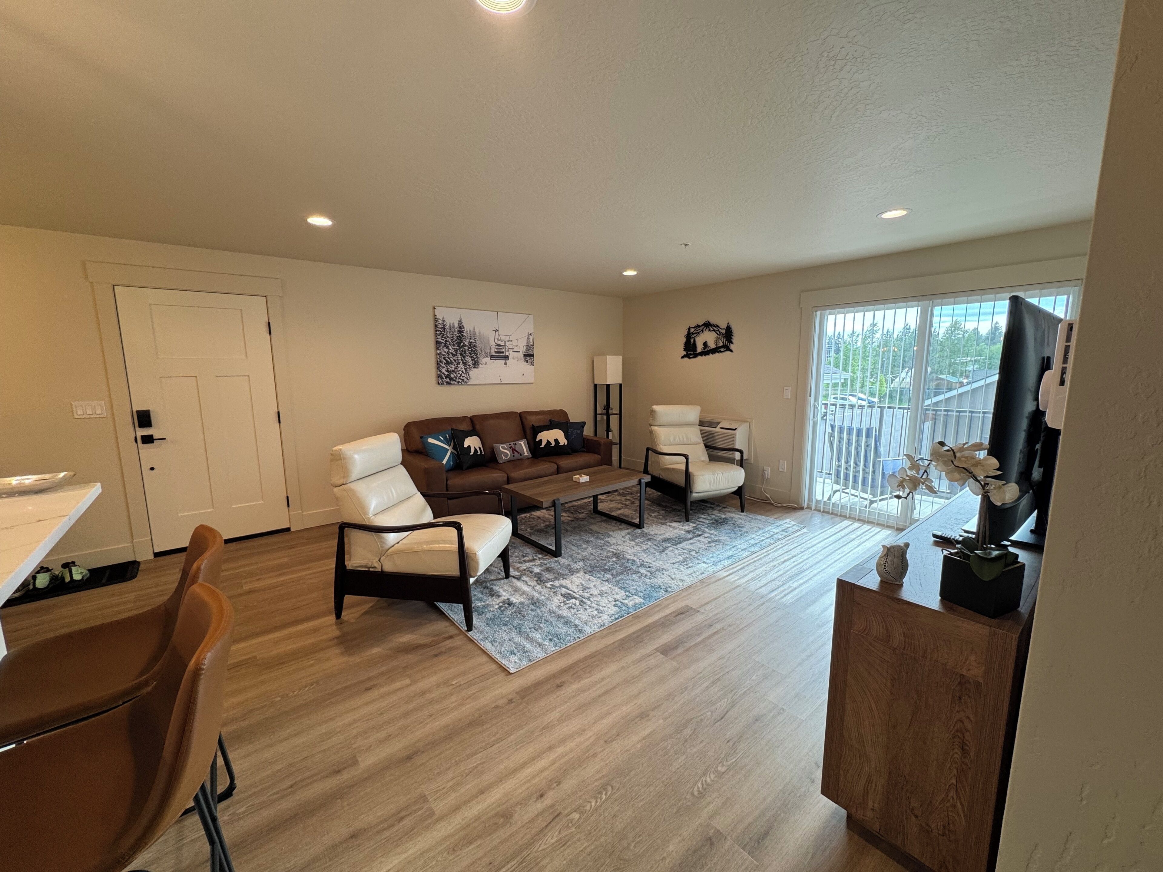 A modern living room with a sofa, armchairs, a coffee table, and a TV.