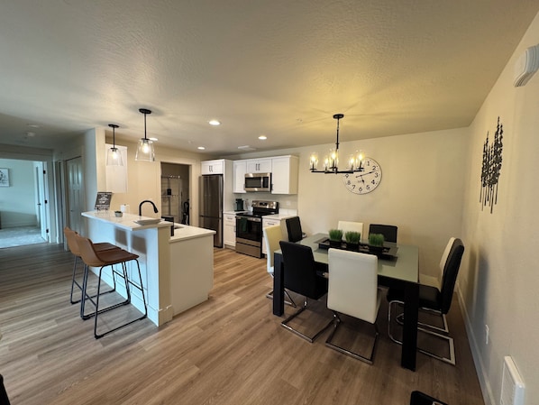 A modern kitchen with white cabinets, stainless steel appliances, and a dining area with a table and chairs.