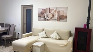 Ein Wohnzimmer mit einer Couch, einem kleinen Tisch und einem Essbereich mit Stühlen.