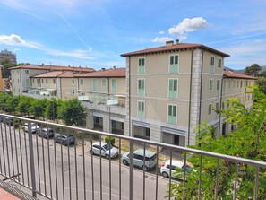 Ein mehrstöckiges Gebäude mit beiger Fassade, grünen Fensterläden und einem Parkplatz mit Autos.