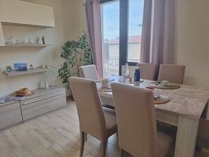 Zona pranzo con tavolo, sedie e una pianta in vaso.
