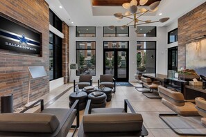 Un hall d’entrée moderne agrémenté d’une enseigne des Dallas Cowboys, de sièges en cuir, d’un bar à café et de grandes fenêtres.