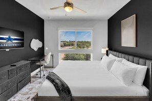 Une chambre moderne avec un grand lit, un bureau, une chaise, une télévision et une fenêtre donnant sur un beau paysage.