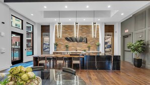 Une cuisine moderne avec un mur de fond en briques, des luminaires suspendus et un îlot central.