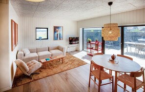 A modern living room with a sofa, coffee table, and dining area with chairs and a table. - Pet friendly home in Hvide Sande with sauna (Hvide Sande)