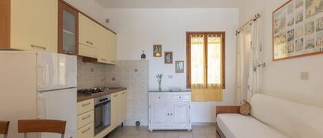 Una cocina compacta con zona de comedor, un sofá y una ventana con cortinas.