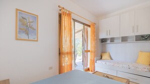 Ein Schlafzimmer mit Bett, Schreibtisch und einem fensterbepflanzten Fenster.