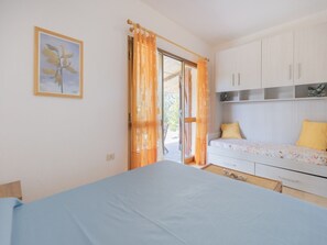 Ein Schlafzimmer mit Bett, Schreibtisch und einem fensterbepflanzten Fenster.
