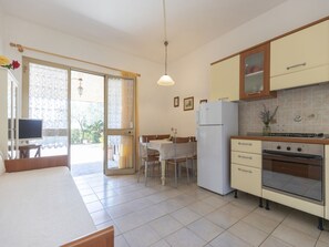 A kitchen with a refrigerator, oven, and dining area with chairs and a table. - Belvedere Sea View Country House (Capoliveri)