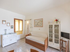 Ein Schlafzimmer mit einem Bett, einem Schrank, einem Fernseher und einem Fenster mit Vorhängen.