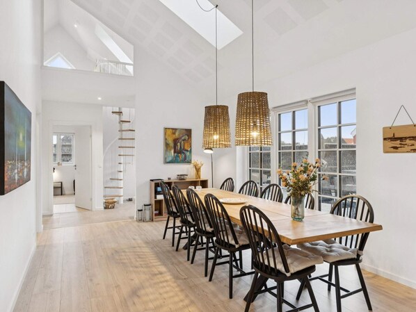 A spacious dining area with a long wooden table, black chairs, and pendant lights. - 4 Star Holiday Home in Skagen (Skagen)