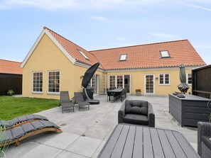 Una casa con patio, que incluye mobiliario exterior, una mesa de comedor y una zona de estar cubierta.