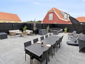 En uteplats med ett bord och stolar, en soffa och en grill.