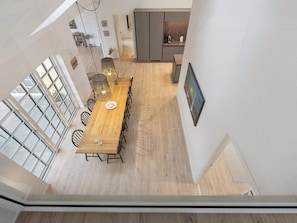 A high-ceilinged dining area with a long wooden table, multiple chairs, and pendant lighting. - 4 Star Holiday Home in Skagen (Skagen)