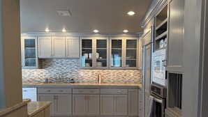 Una cocina moderna con gabinetes grises, salpicadero de azulejos y electrodomésticos integrados.