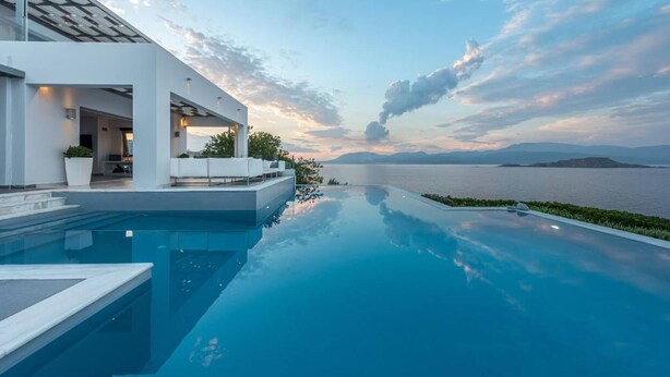 Ein moderner Infinity-Pool mit Blick auf Meer und Berge.