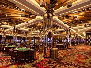 Ein Casino mit mehreren Blackjack-Tischen, Spielautomaten und einem lebhaften, gemusterten Teppich.