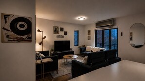 Un soggiorno moderno con una TV a schermo piatto, un divano, un tavolino da caffè e un'area pranzo.