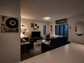 Ein modernes Wohnzimmer mit Flachbildfernseher, Sofa, Couchtisch und Essbereich.
