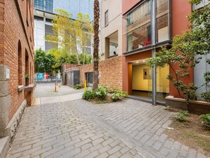Ein gepflasterter Innenhof mit Backsteingebäuden, einer Palme und einer gelben Eingangstür.