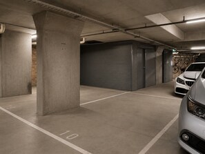 A parking garage with concrete pillars, a white car, and a garage door. - Skyline Suites | New York-Style Riverside Retreat (Southbank)
