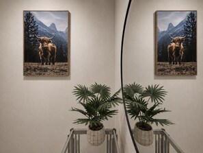 Zwei gerahmte Bilder von einem Jak, einer Topfpflanze und einem Heizkörper.