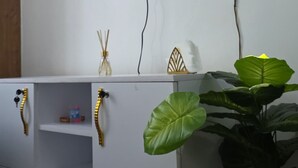 A television mounted on a wall displaying a fireplace, a white cabinet with decorative handles, and a potted plant. - Delightful Executive Studio in Kiambu, family friendly and relaxing. (Kiambu Province)