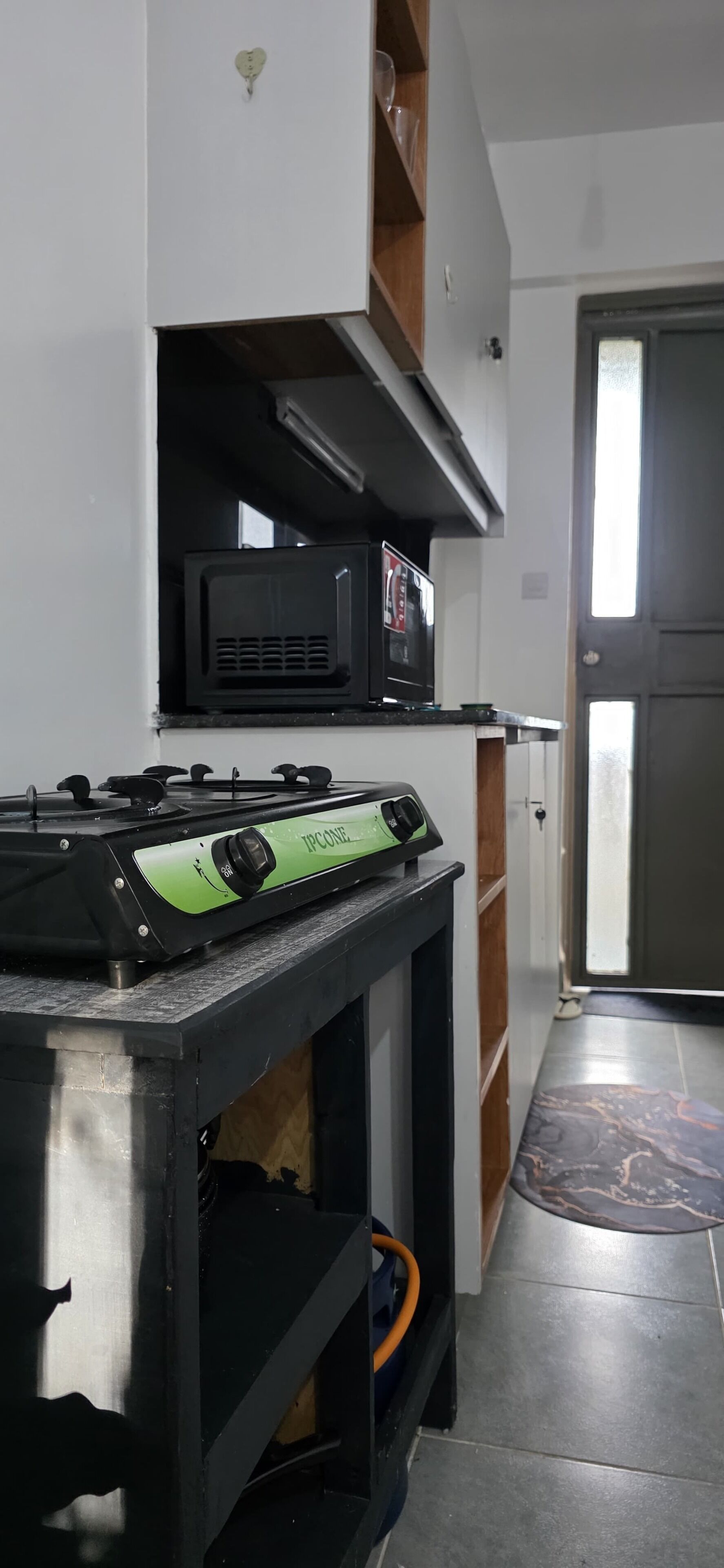 A kitchen with a gas stove, a microwave, and a cabinet.