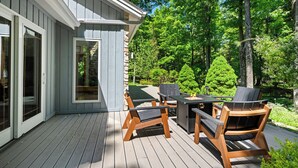 Eine Terrasse im Freien mit Tisch und Stühlen, einer Steinmauer und Blick auf einen Wald.
