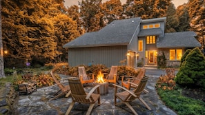 A house with a stone patio, outdoor seating, and a fire pit.