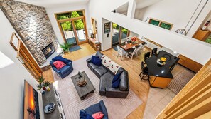 A spacious living area with a stone fireplace, a dining table set for four, and a kitchen area with a black countertop.