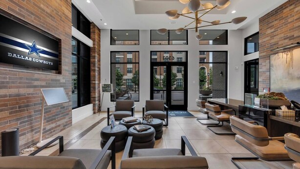 En modern entréhall med en skylt med Dallas Cowboys-logotypen, lädersitsar, en kaffebar och stora fönster.