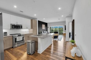 Une cuisine moderne dotée d’appareils électroménagers en acier inoxydable, d’un grand îlot central et offrant une vue sur l’extérieur.