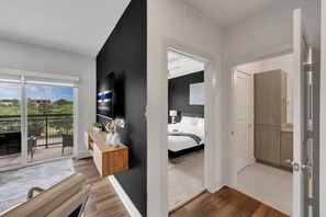 Une chambre d’hôtel moderne dotée d’un balcon, d’un téléviseur à écran plat, d’une console en bois, d’un lit et d’une armoire.