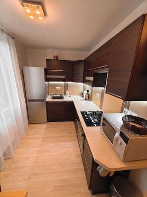 Eine moderne Küche mit dunklen Holzschränken, Edelstahlgeräten und einer hellichtfarbenen Arbeitsplatte.