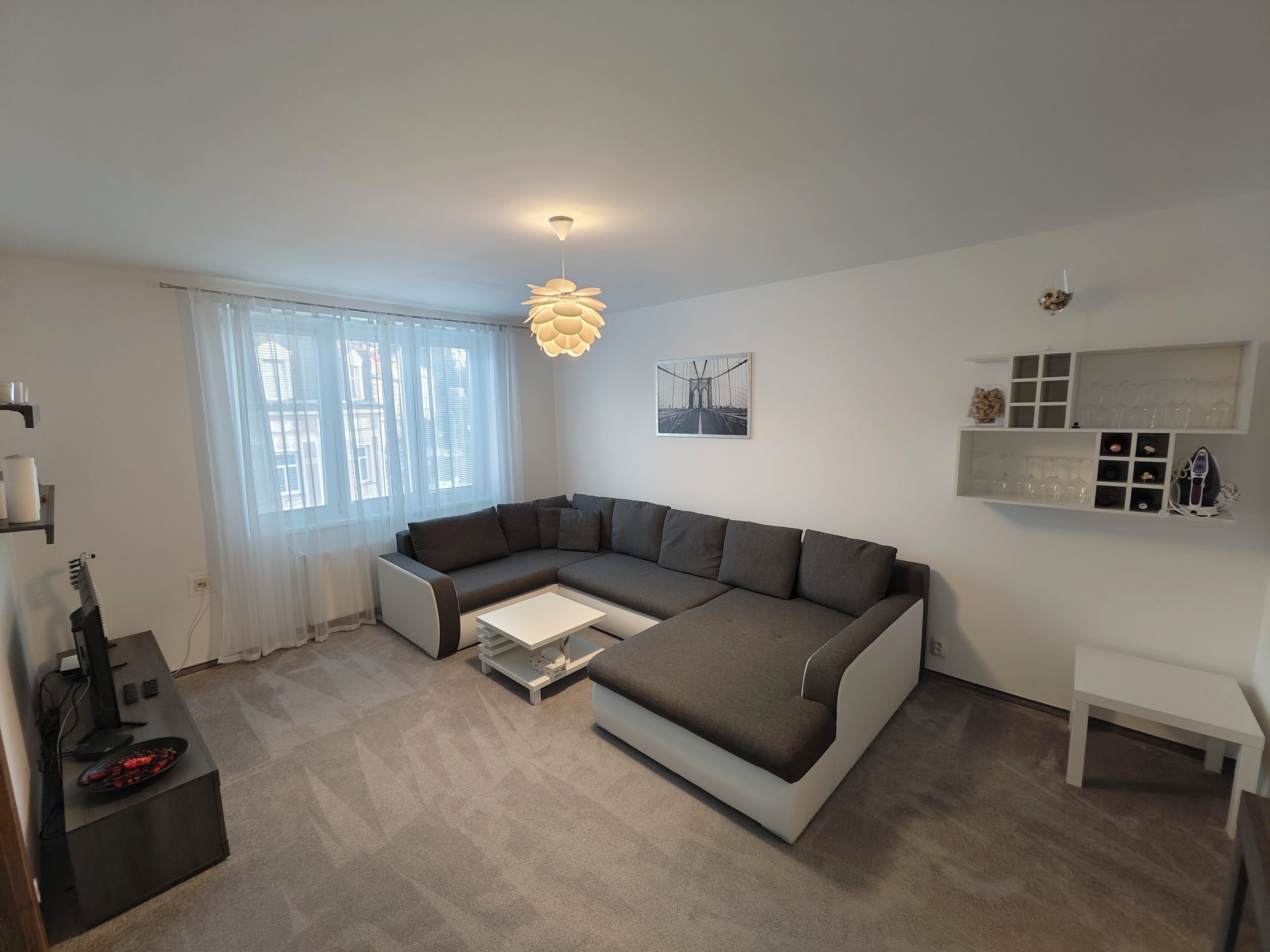 Una sala de estar moderna con un sofá modular, una mesa de centro, un ventilador de techo y un estante de pared con vasos.