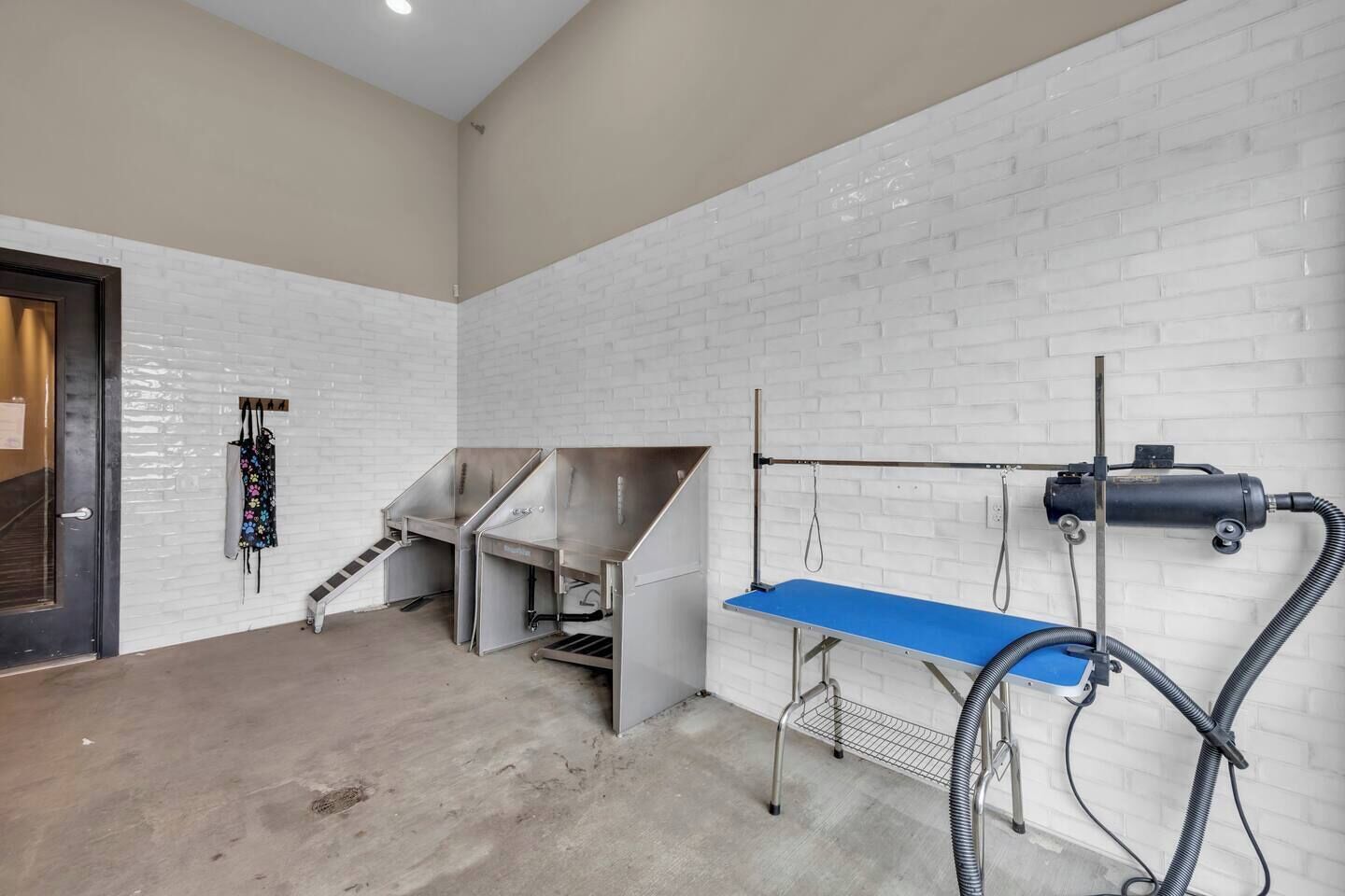 Ein Zimmer mit einer weißen Backsteinwand, einem blauen Tisch und einer Metallmaschine.